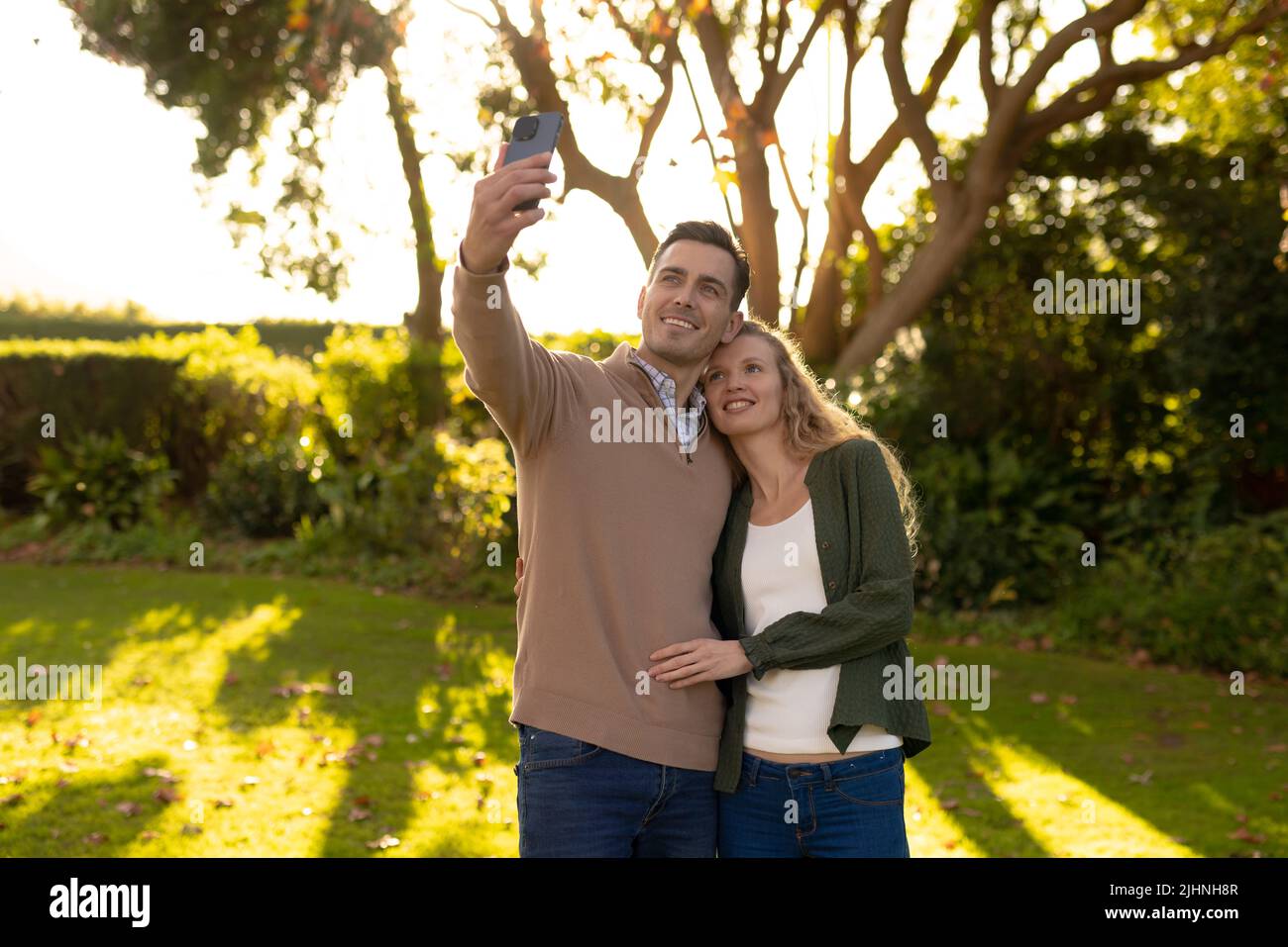 Image d'un couple caucasien heureux prenant le selfie dans le jardin Banque D'Images