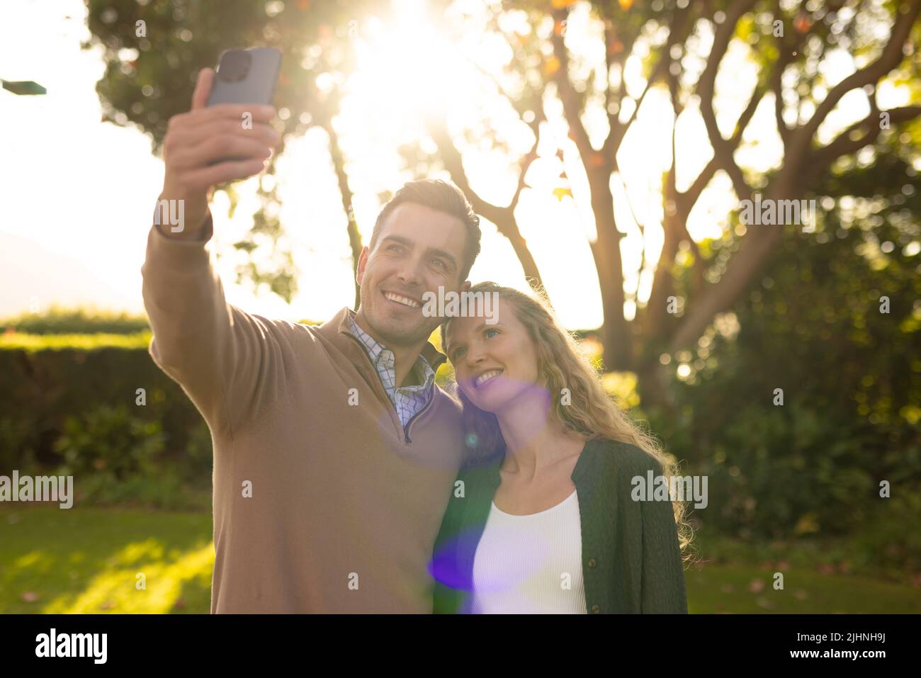 Image d'un couple caucasien heureux prenant le selfie dans le jardin Banque D'Images