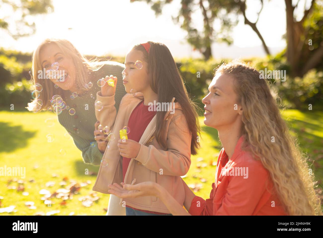 Image de femmes caucasiennes de trois générations heureuses avec des bulles de savon dans le jardin Banque D'Images