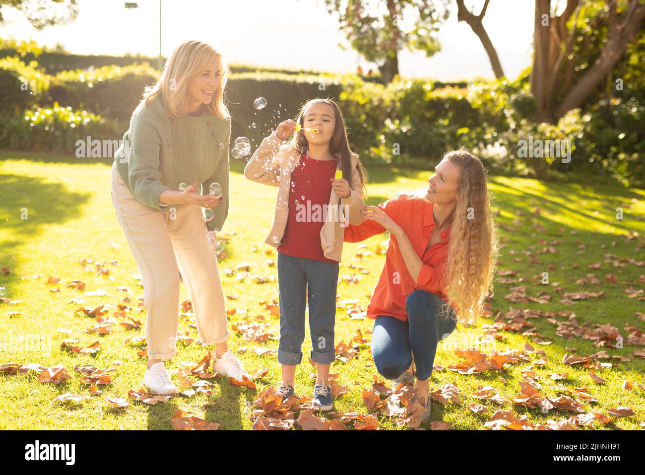 Image de femmes caucasiennes de trois générations heureuses avec des bulles de savon dans le jardin Banque D'Images