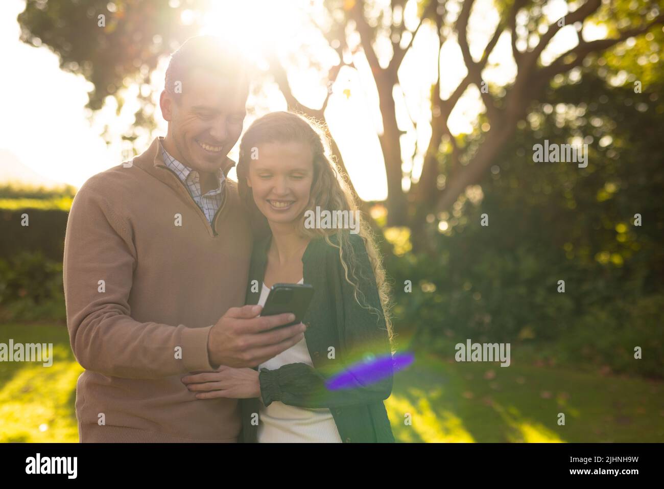 Image d'un couple caucasien heureux prenant le selfie dans le jardin Banque D'Images