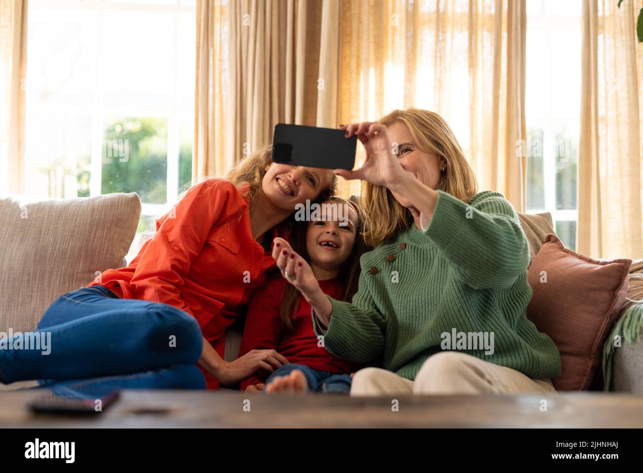 Image de femmes caucasiennes de trois générations heureuses assises sur un canapé et prenant le selfie Banque D'Images