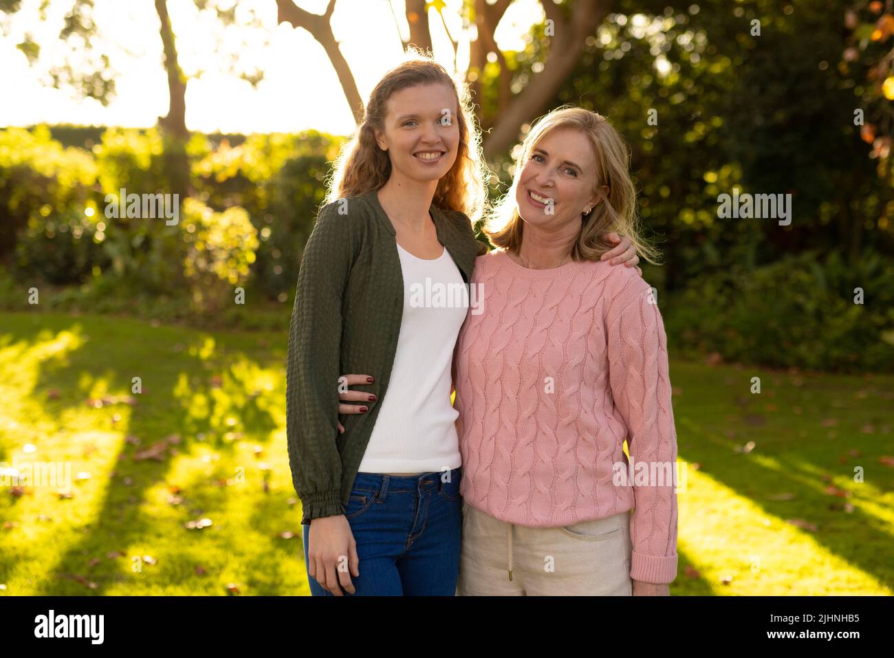 Image de la bonne mère caucasienne et de la fille adulte posant à l'appareil photo dans le jardin d'automne Banque D'Images