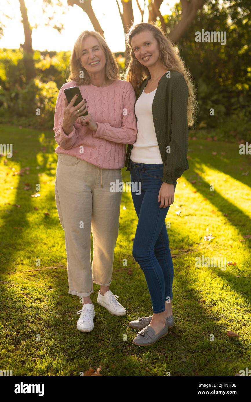 Image verticale de la bonne mère caucasienne et de la fille adulte posant à l'appareil photo dans le jardin d'automne Banque D'Images
