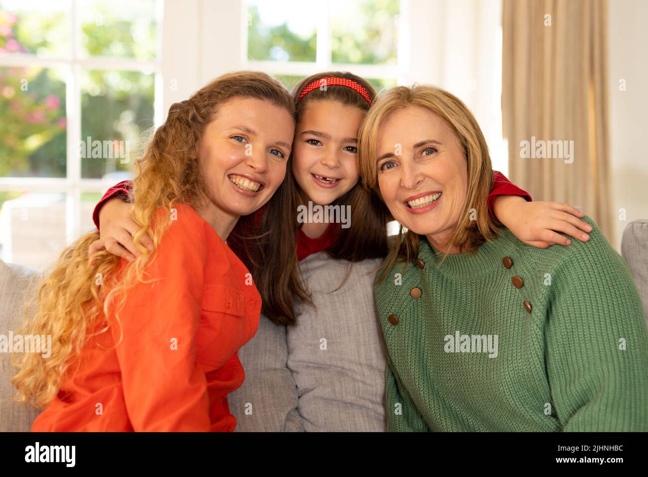 Image de femmes caucasiennes de trois générations heureuses assises sur un canapé et embrassant Banque D'Images