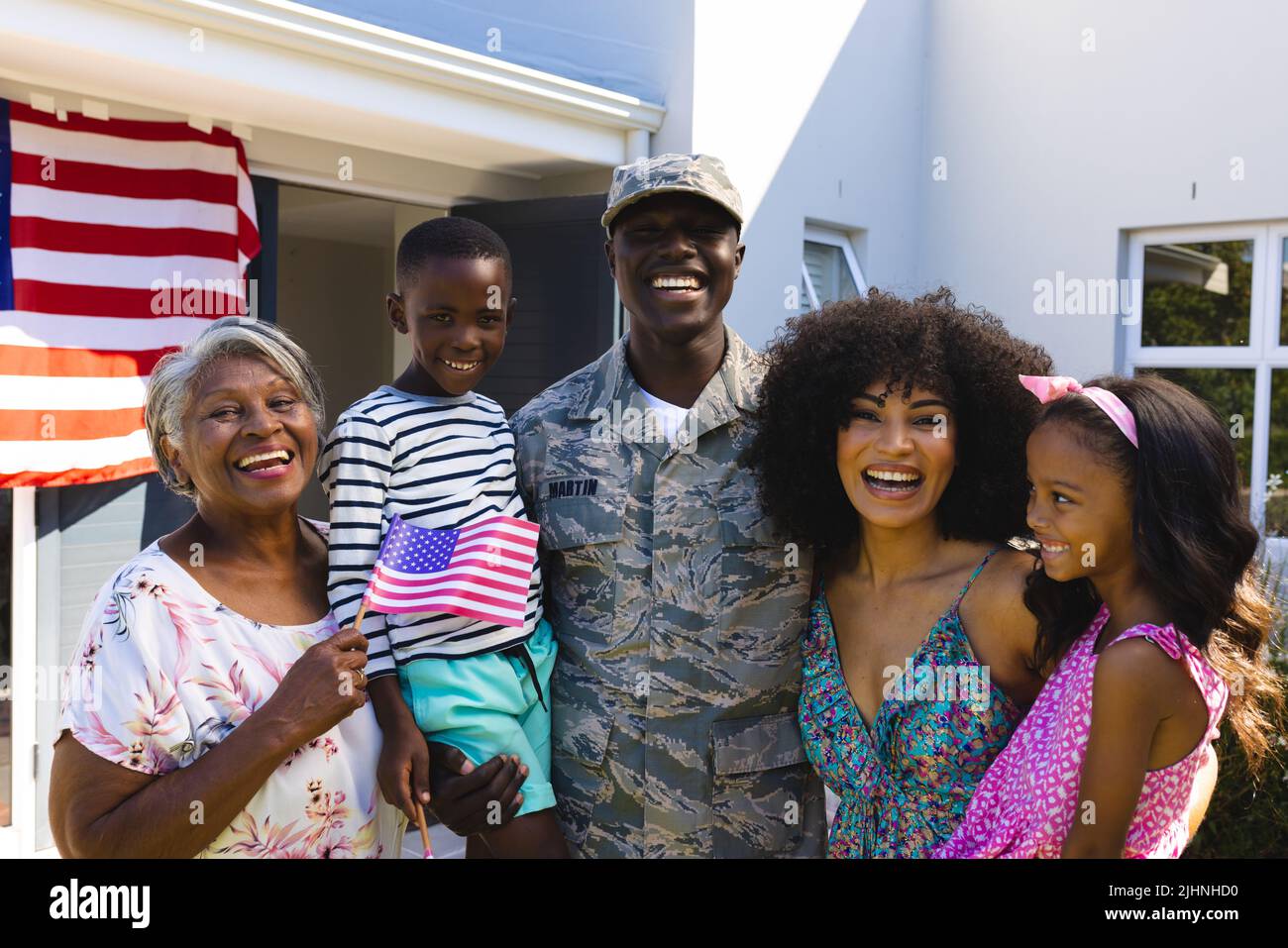 Portrait d'un soldat multiracial heureux de l'armée dans des vêtements de camouflage avec la famille debout dans la cour Banque D'Images