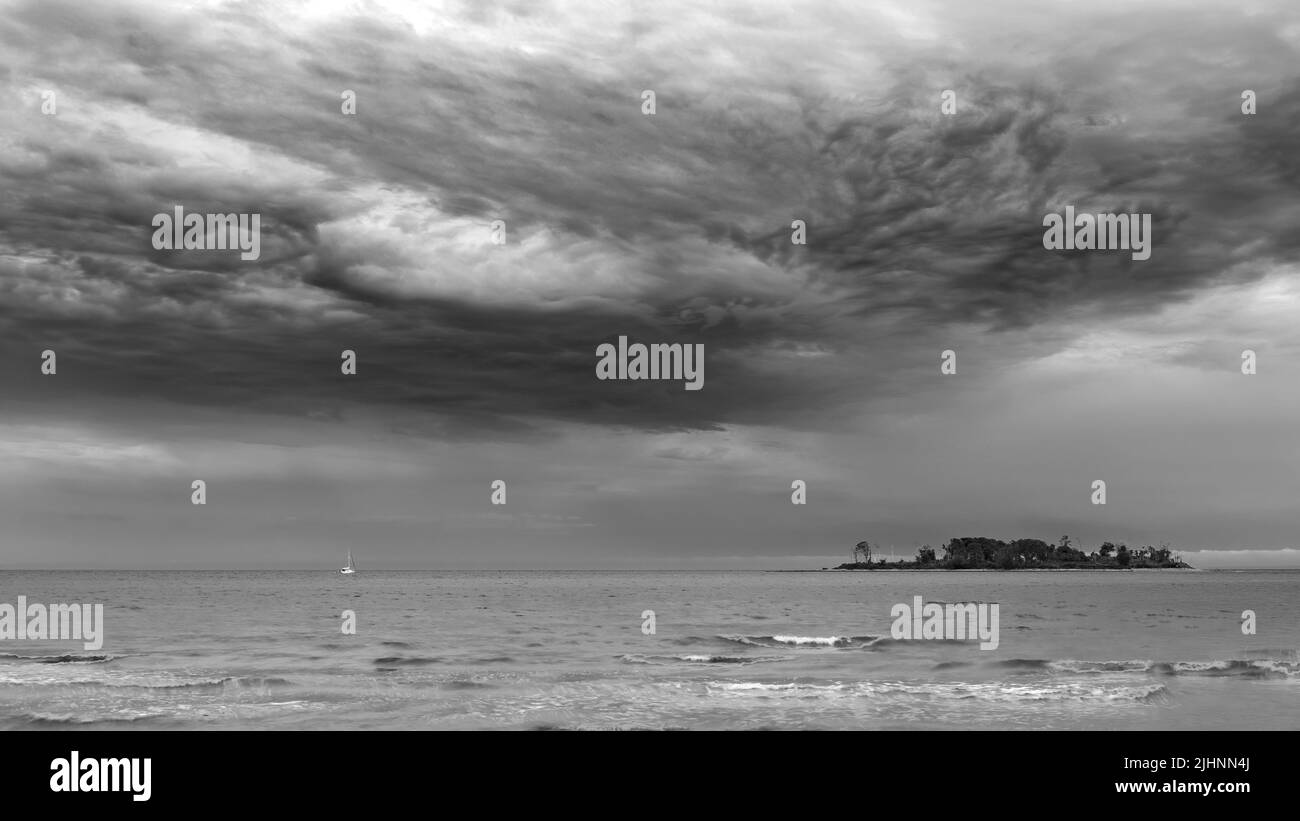 Nuages de tempête au-dessus de Small Island et de Tiny Boat Banque D'Images