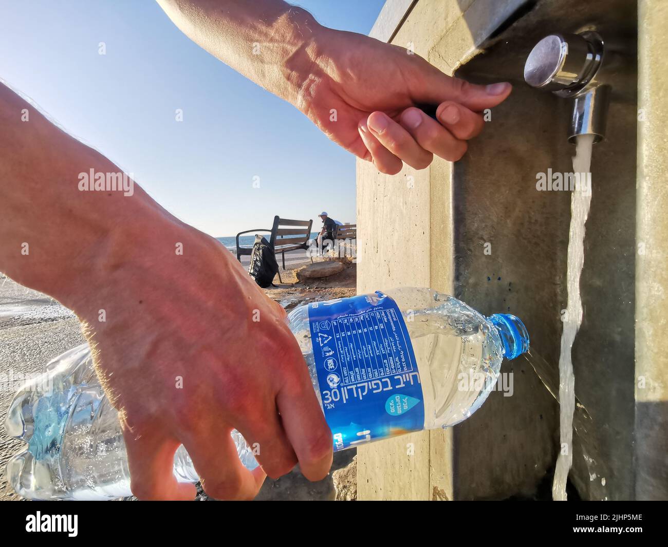 Tel Aviv, Israël. 19th juillet 2022. Un homme remplit une bouteille d'eau dans un distributeur d'eau potable situé sur la promenade de la plage, longue d'un kilomètre. Remplissez la bouteille d'eau et vous avez terminé. Cela protège non seulement contre les coups de soleil, mais permet également d'économiser de l'argent dans l'une des villes les plus chères du monde. (À dpa 'Qatar à la Californie: Comment les métropoles chaudes traitent la chaleur') Credit: Christina Storz/dpa/Alamy Live News Banque D'Images