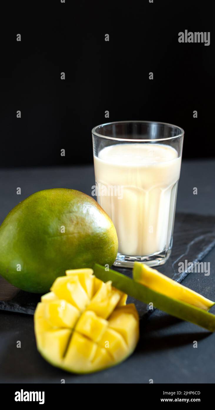 Boisson au lait sur fond noir à la mangue. Un milkshake à la mangue classique - Lassi. Une boisson traditionnelle en Inde de la chaleur Banque D'Images