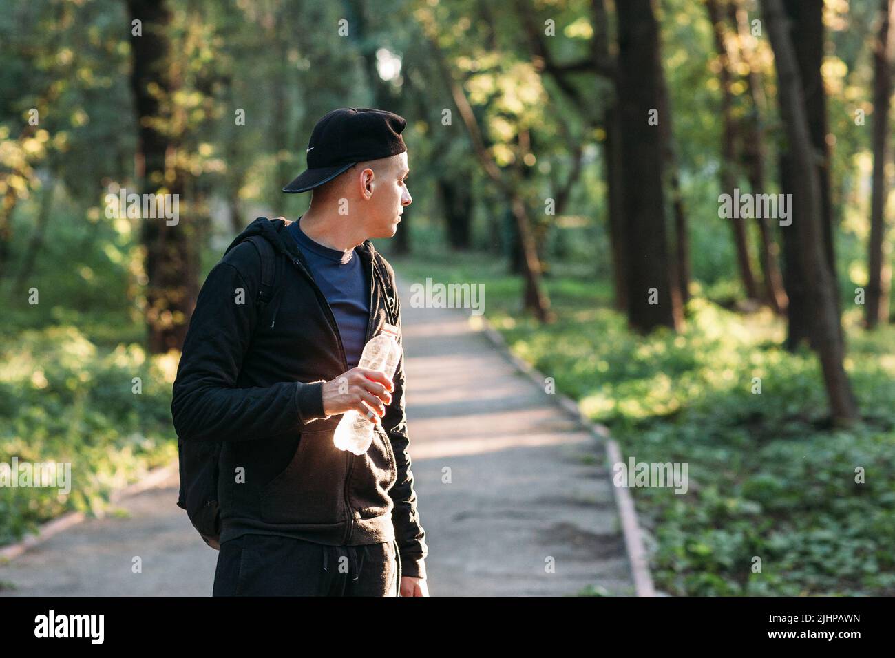 Jeune homme regardant en arrière sur la route de la forêt, espace libre Banque D'Images