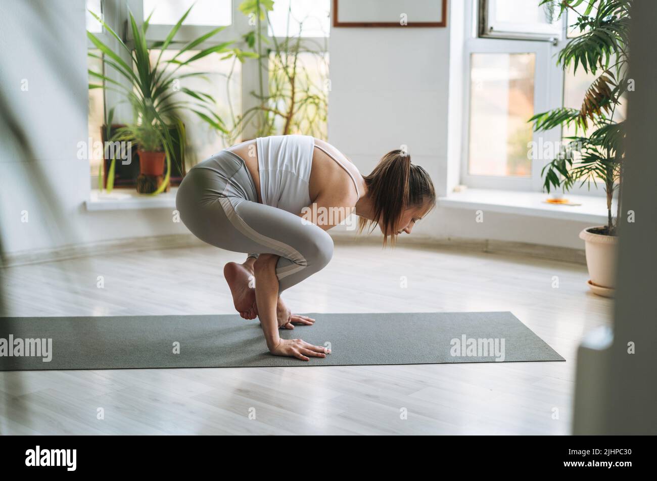 Une jeune femme en forme pratique le yoga faisant de l'asana dans un studio de yoga léger avec des plantes vertes Banque D'Images