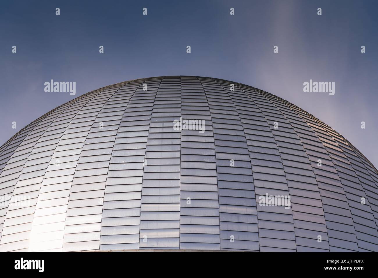 Carreaux argentés sur un dôme d'un bâtiment avec un reflet du soleil sur le ciel bleu foncé Banque D'Images