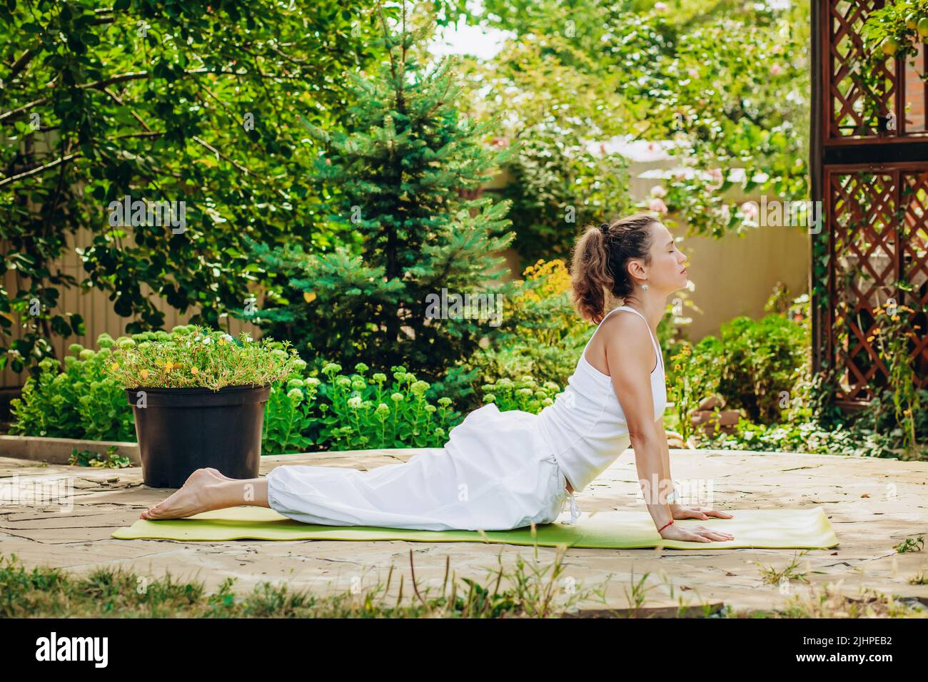 Une jeune femme pratique le yoga dans le jardin. Surya namaskar, posture de Bhujangasana Cobra. Banque D'Images