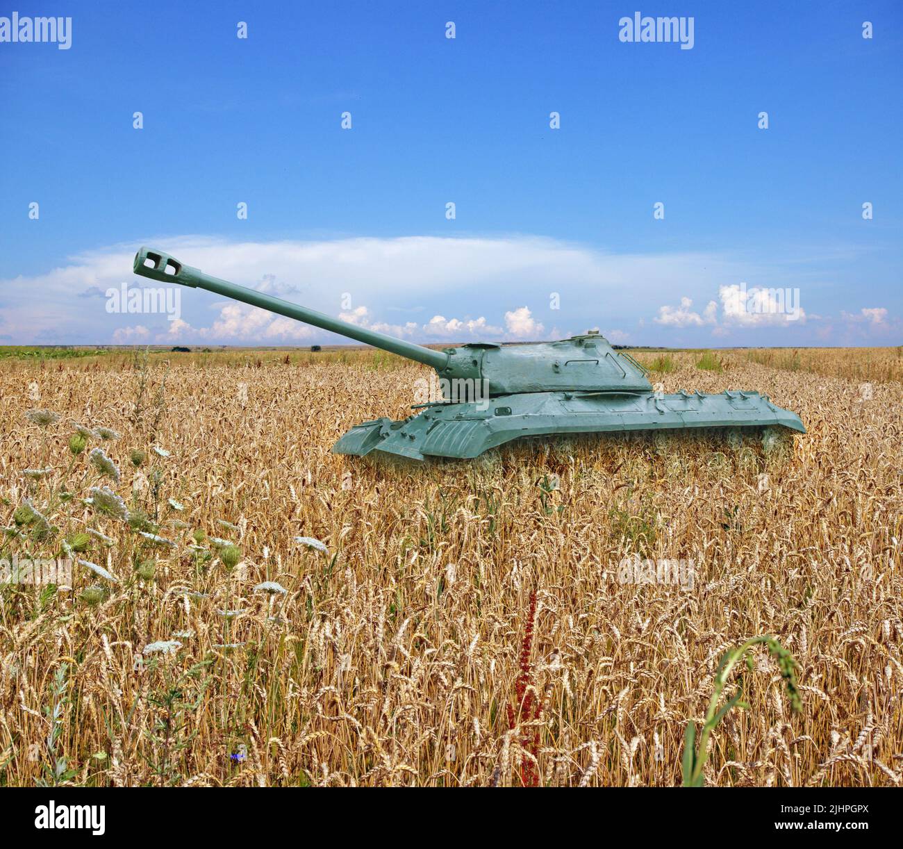 Ancien réservoir sur un champ de blé jaune et ciel bleu avec des nuages à l'horizon. Le concept de guerre en Ukraine Banque D'Images