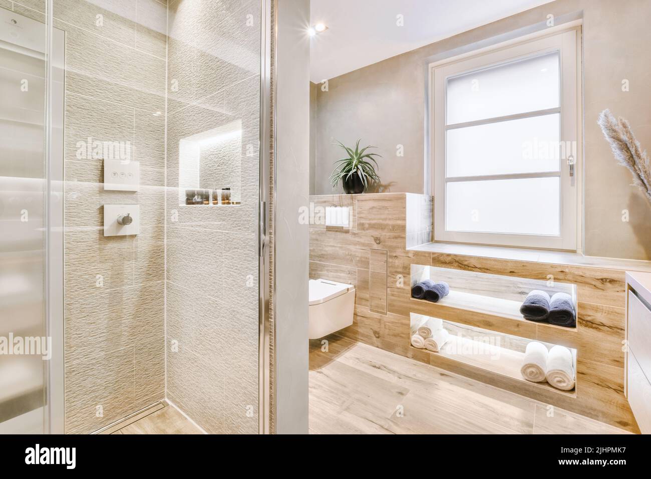 Meuble-lavabo et meuble miroir dans la salle de bains carrelée de blanc avec toilettes accrochées au mur Banque D'Images