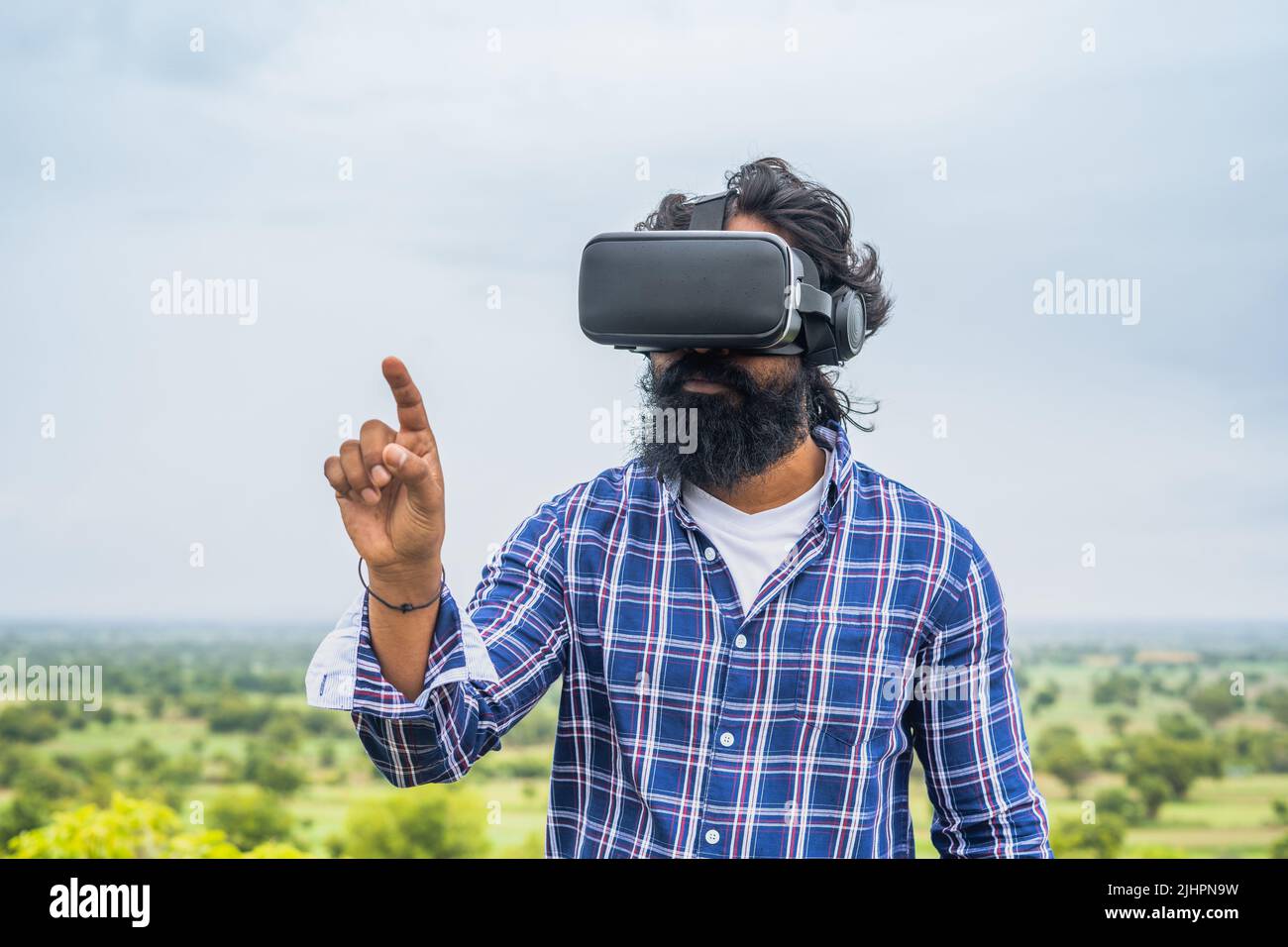 Jeune homme de barbe utilisant VR au sommet de la colline en touchant les gestes de la main sur la nature - concept d'interaction virtuelle, d'innovation et de divertissement. Banque D'Images