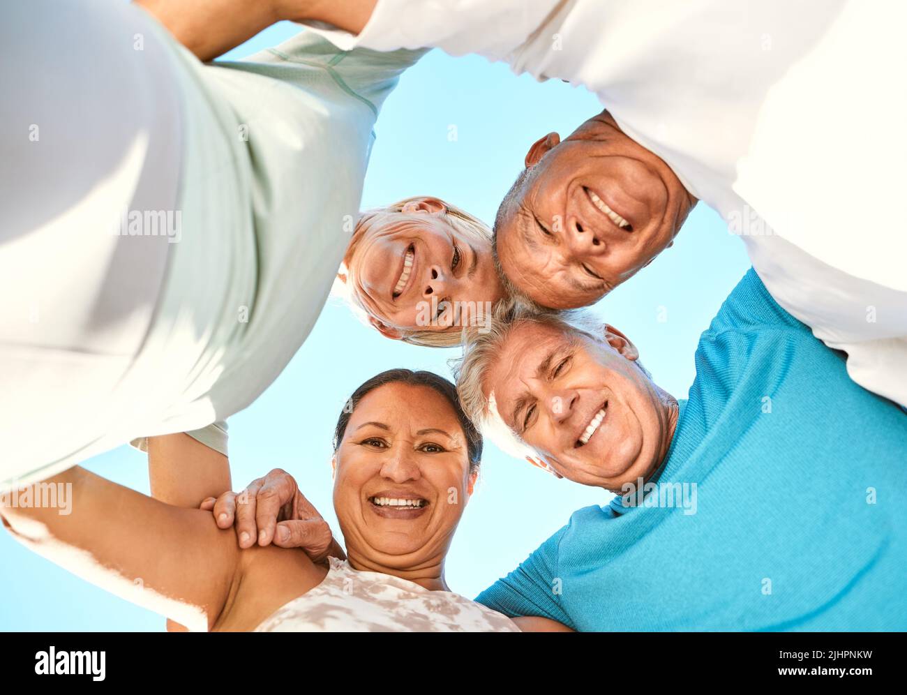 Vue en dessous d'un portrait d'un groupe d'amis âgés debout ensemble dans un caucus. Souriant, des personnes âgées actives se sergent tout en regardant la caméra Banque D'Images