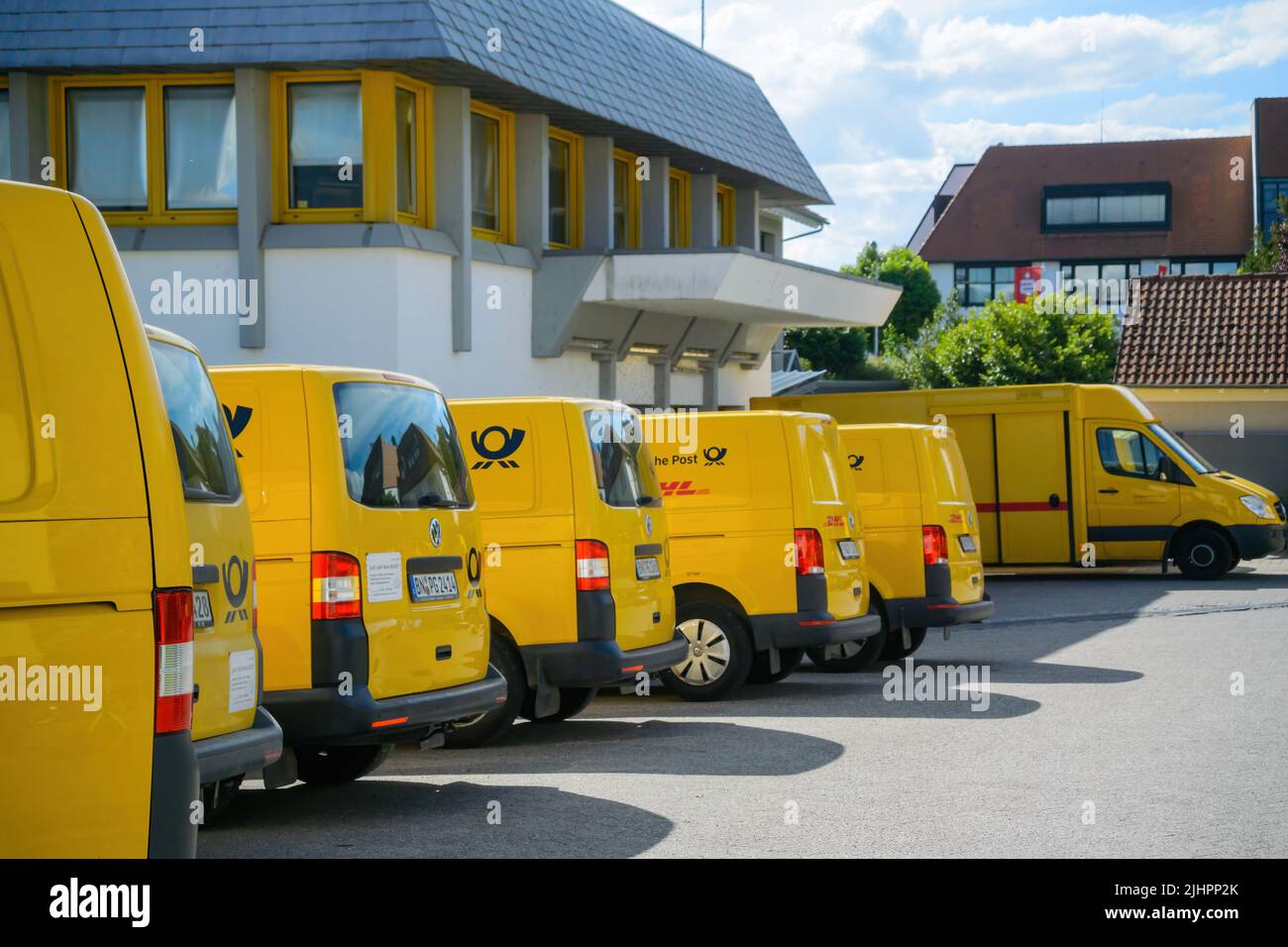 Oberkirch, Allemagne - 27 mai 2022: Vue latérale de la rangée de multiples fourgonnettes électriques jaunes Volkswagen avec le logotype Deutsche post DHL - garée près du centre de distribution postal Banque D'Images