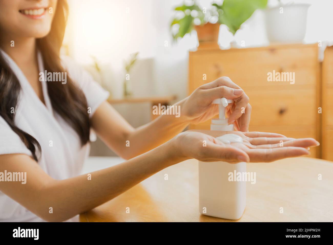 Gros plan de la main de la femme presser le flacon de crème de lotion pour la peau pour appliquer hydratant sur sa main, le traitement et les soins du corps Banque D'Images