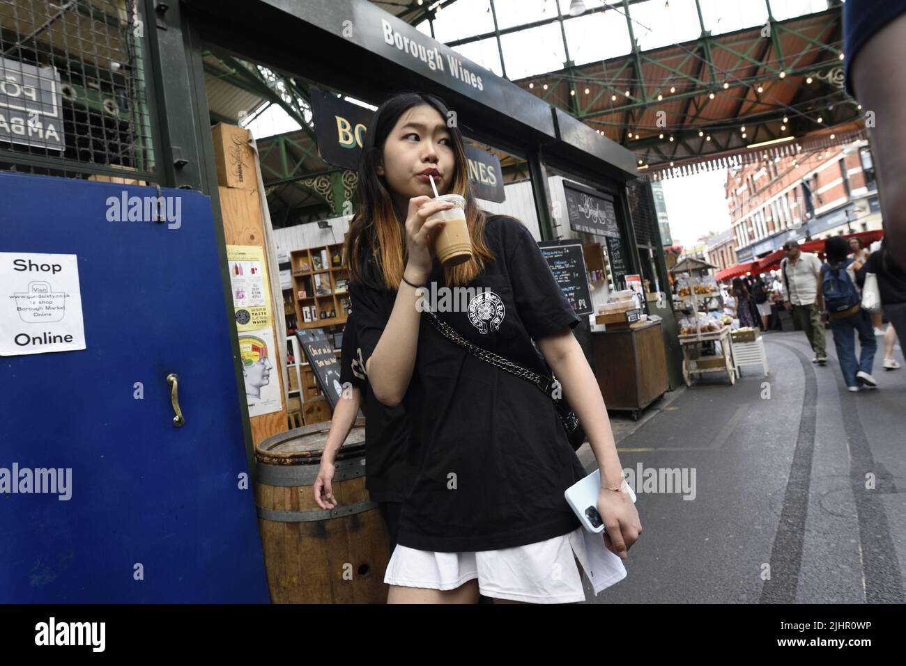 Londres, Angleterre, Royaume-Uni. Marché de quartier, Southwark. Une jeune femme asiatique boit du café à emporter Banque D'Images