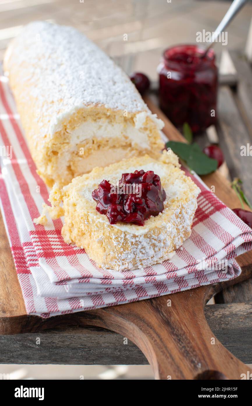 Dessert à la cerise avec un rouleau suisse rempli de crème fouettée et recouvert de compote Banque D'Images