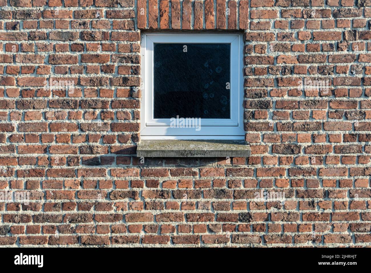 Petite fenêtre au milieu d'un mur de briques rouges Banque D'Images