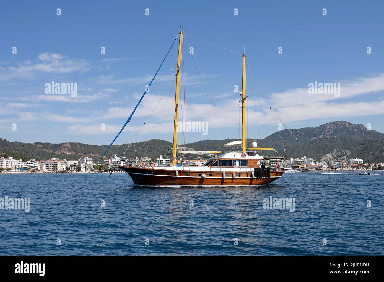 Yacht avec voiles abaissées dans la baie bleue de la mer Méditerranée sur la ville de station de Marmaris et les montagnes arrière-plan en été Banque D'Images