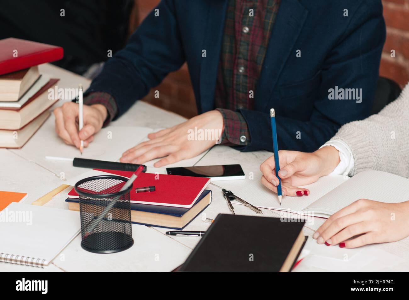 Homme et femme méconnaissables écrivant à leur bureau Banque D'Images