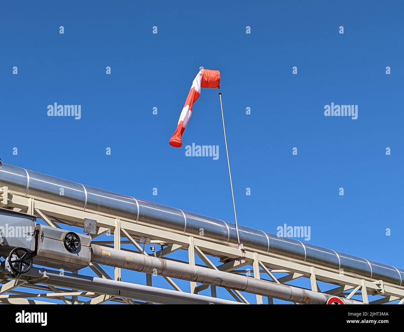 Photo basse d'une chaussette rouge et blanche sur un tube métallique contre un ciel bleu Banque D'Images