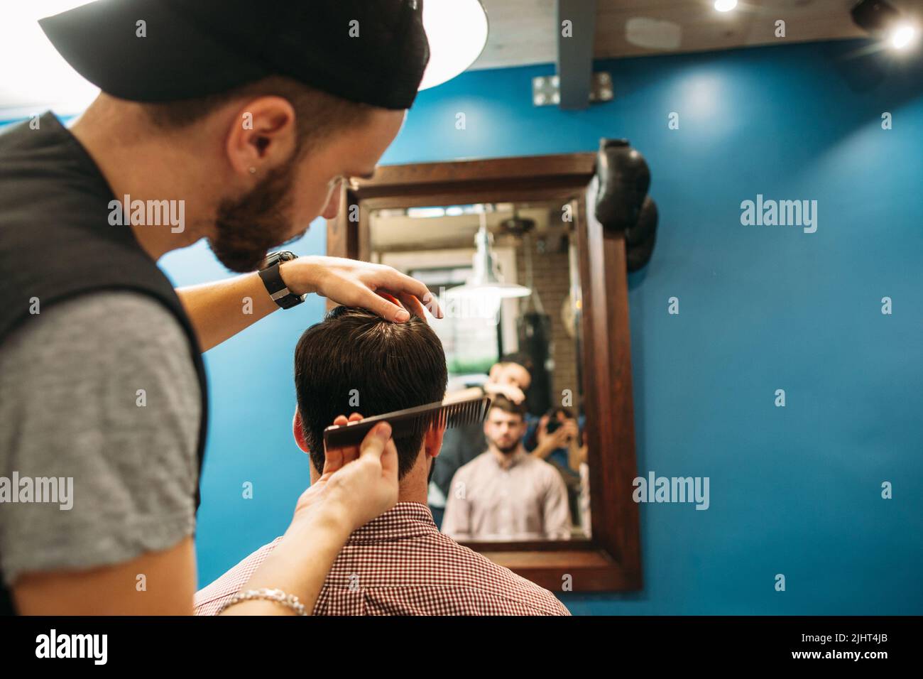 Un jeune styliste coupe le client dans l'espace libre du miroir Banque D'Images