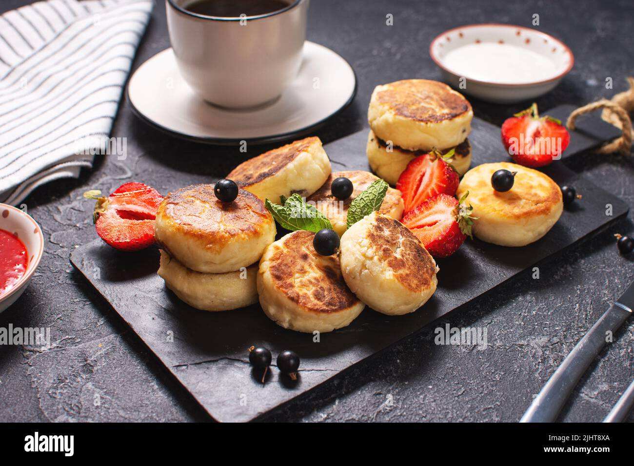 Crêpes au fromage cottage, beignets de ricotta ou syrniki avec cassis et fraises. Petit déjeuner sain et délicieux Banque D'Images