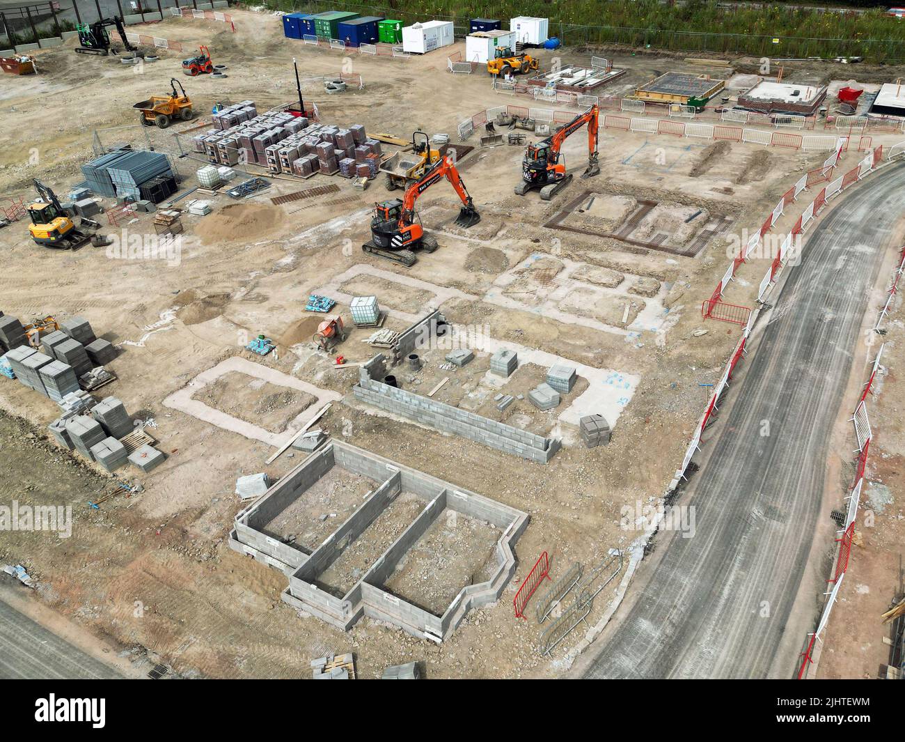Pontypridd, pays de Galles - juillet 2022 : vue aérienne des excavateurs mécaniques garés le long des bases pour de nouvelles maisons dans un développement de logements dans le sud du pays de Galles. Banque D'Images Pontypridd, pays de Galles - juillet 2022 : vue aérienne des excavateurs mécaniques garés le long des bases pour de nouvelles maisons dans un développement de logements dans le sud du pays de Galles. Banque D'Images