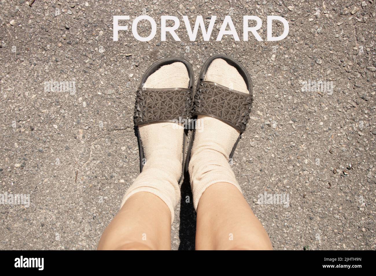 pieds femelles en chaussettes et pantoufles sur asphalte gris, pieds femelles sur la route Banque D'Images