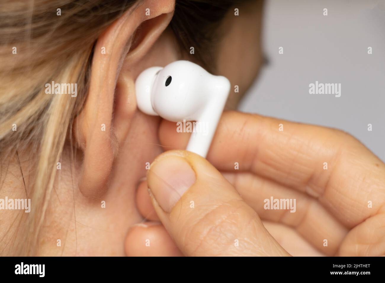Casque blanc sans fil dans l'oreille d'une fille gros plan, écoutez de la musique dans un casque, un casque sans fil, de la musique Banque D'Images