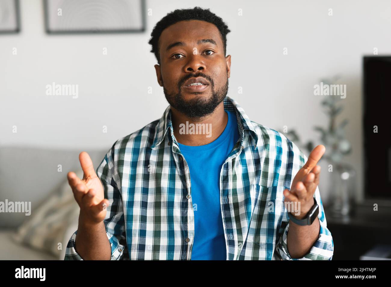Un homme afro-américain sérieux qui parle assis à la maison Banque D'Images