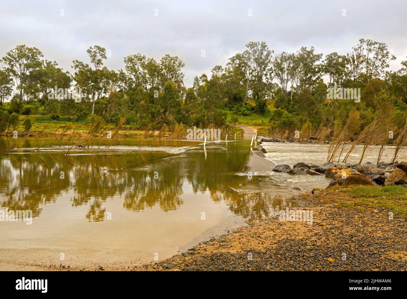 L'eau de la rivière Burnett s'écoulant sur le pont bas / pont-jetée à Booyal Crossing avec forêt d'arbres reflétés dans la surface miroir, près de Childers Australie Banque D'Images