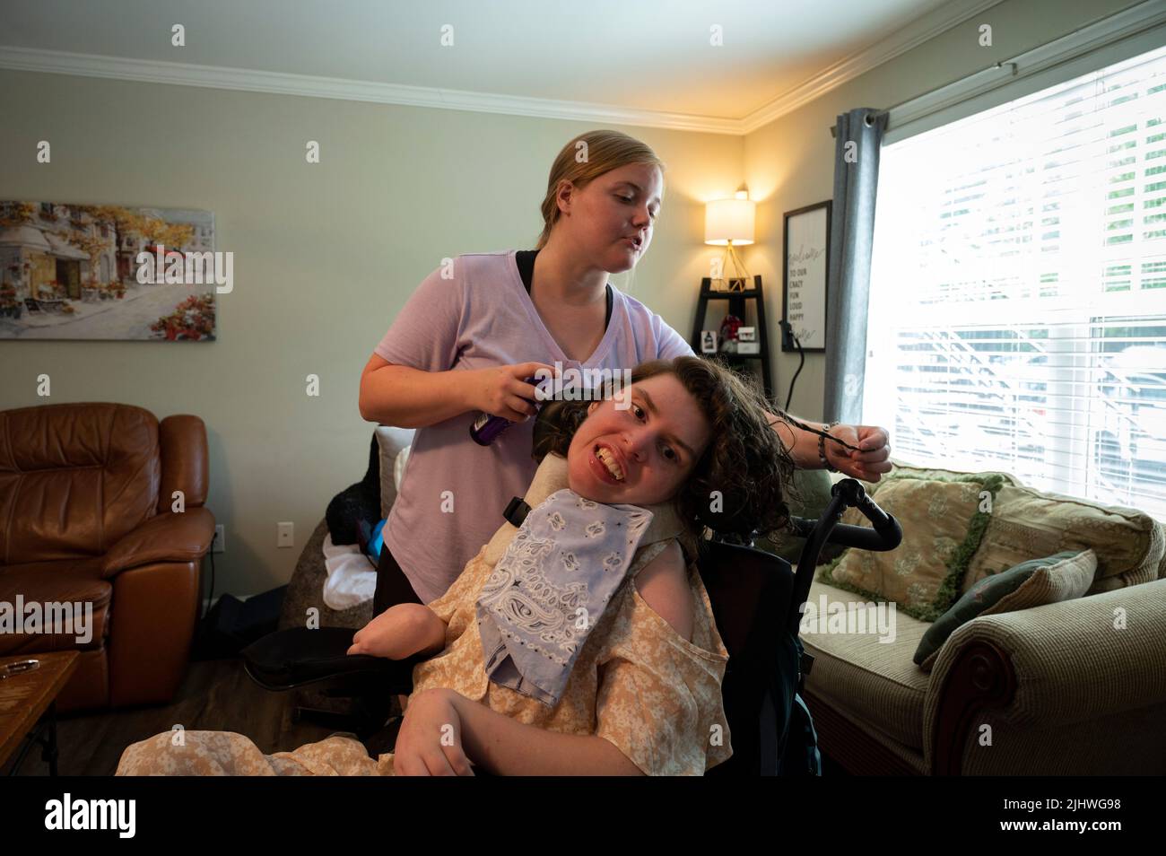 Athènes, Géorgie, États-Unis. 19th juillet 2022. Les professionnels du soutien direct qui aident et prennent soin des personnes handicapées vivant dans leur propre foyer sont de plus en plus rares, en grande partie en raison des bas salaires horaires dans la face de l'inflation. Les organisations à but non lucratif qui gèrent les soignants sont frustrées par des fonds limités provenant des budgets de dispense Medicaid de l'État, mettant des milliers de personnes dans la population nationale de personnes handicapées à risque, selon les défenseurs de l'invalidité. Photo : Mackenzie Bramblett, 27 ans, présente les cheveux de Callie Moore dans l'appartement de Callie. Callie, 27 ans, qui est médicalement fragile avec de multiples p Banque D'Images