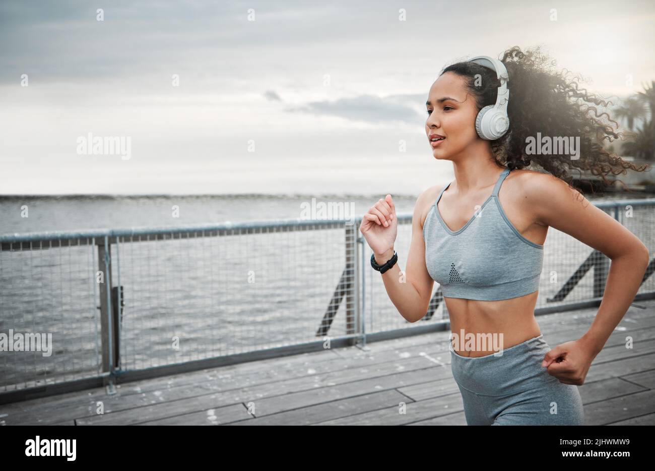 Une jeune athlète féminine attirante qui écoute de la musique pendant sa course matinale à l'extérieur. Banque D'Images