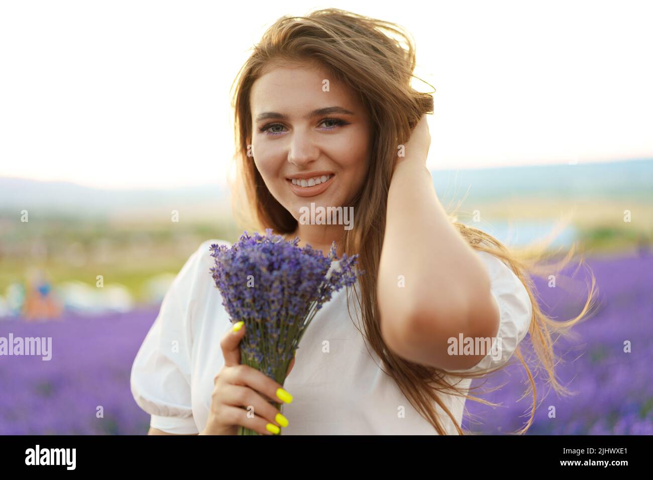 Gros plan portrait d'une jeune femme tenant un bouquet de lavande blaniile debout dans le champ de lavande Banque D'Images