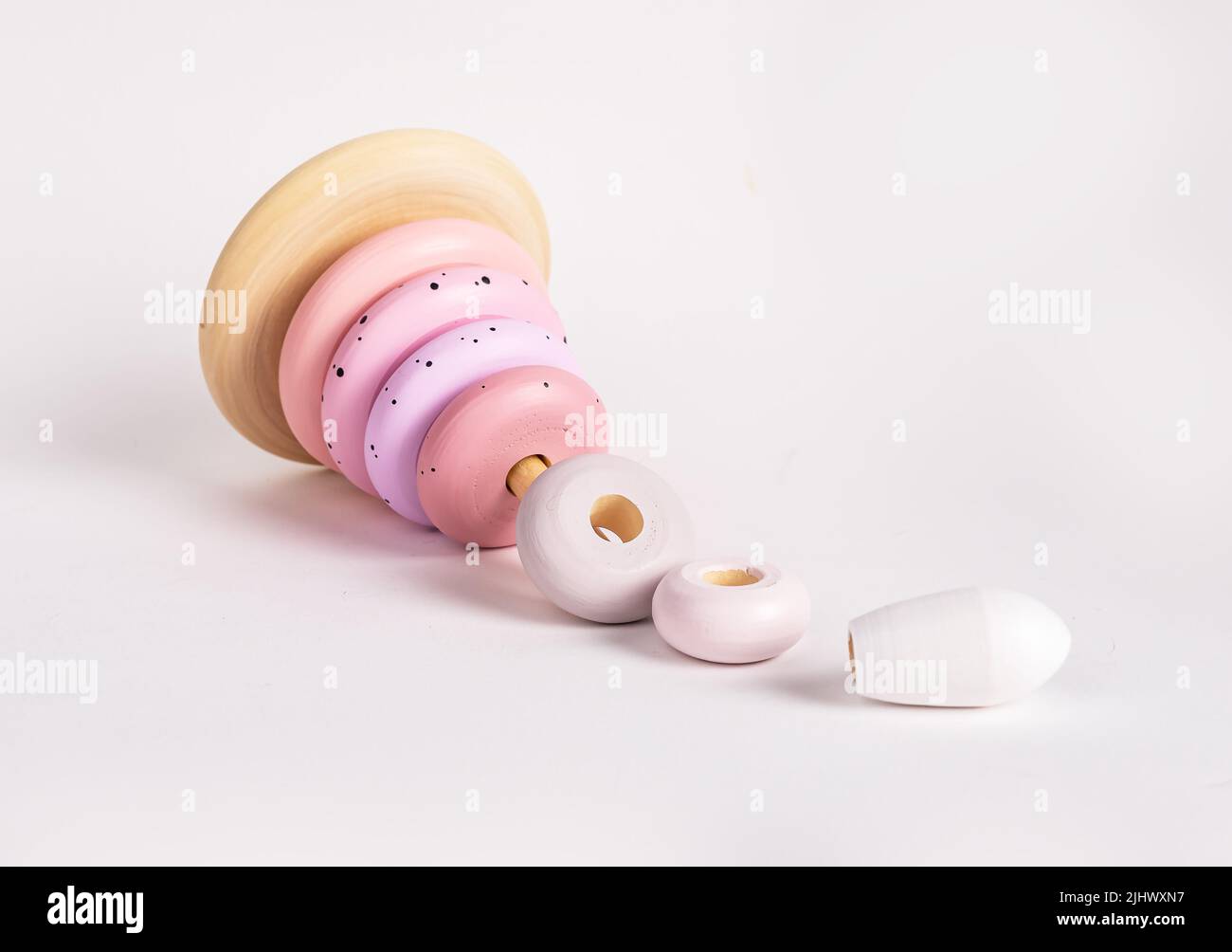 Chute de pyramide en bois. Jouet d'apprentissage pour enfant en rose tendre, couleurs pastel. Développement de la coordination main-œil. Jeu Montessori . Photo de haute qualité Banque D'Images