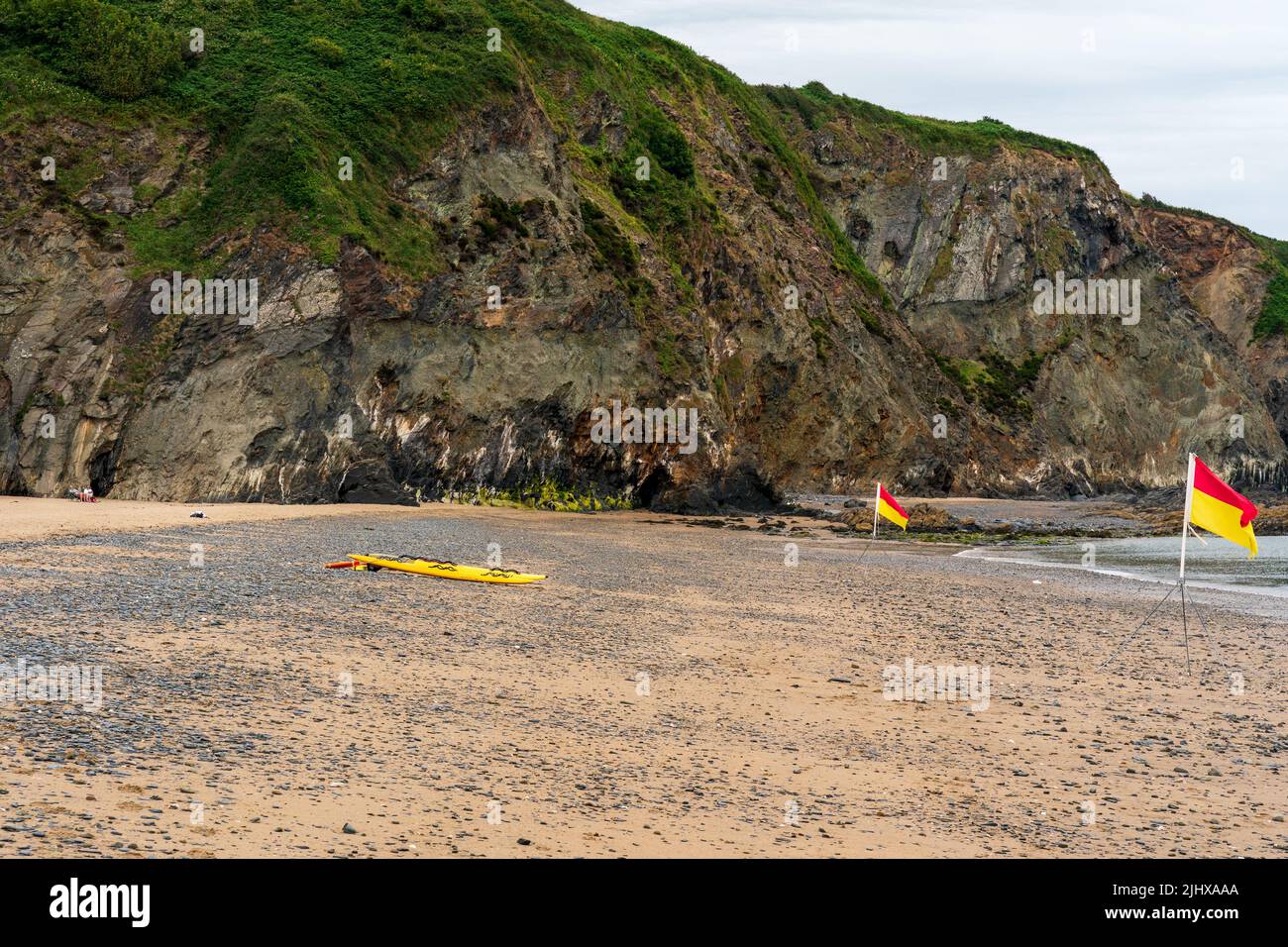 Zone de sécurité de la plage pour nager les drapeaux et les sauveteurs paddle board à Tresaith Ceredigion West Wales Royaume-Uni Banque D'Images
