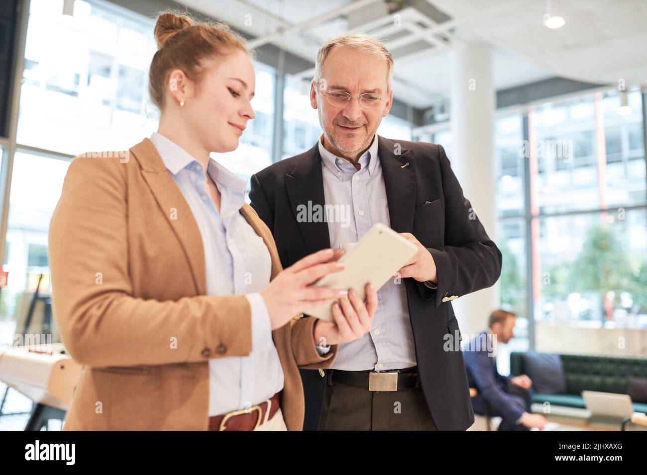 Manager senior et jeune femme d'affaires avec un Tablet pc utilisant une application d'information au bureau Banque D'Images