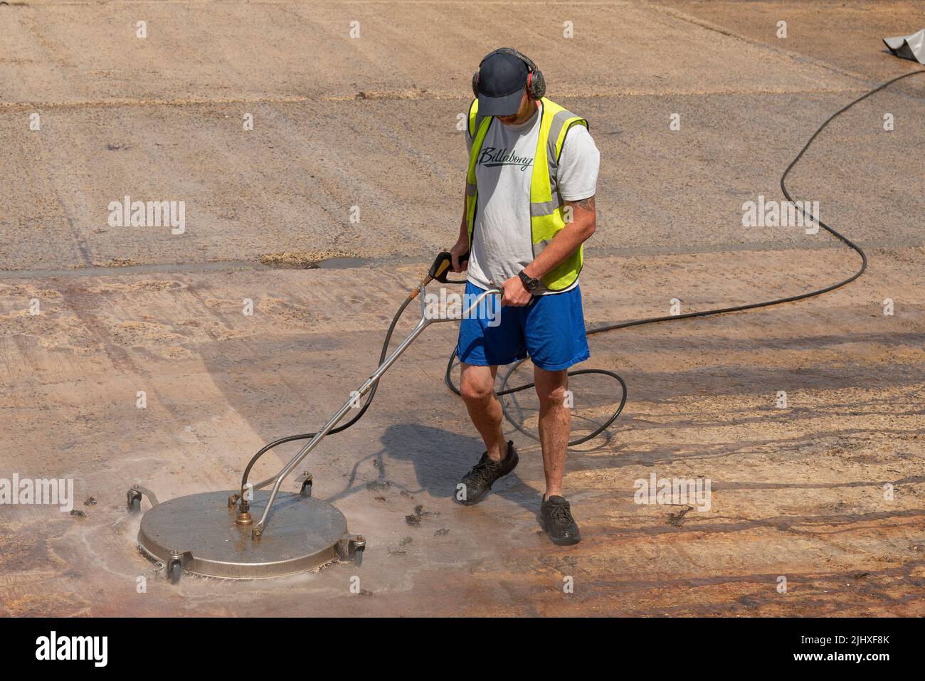 Falmouth, Cornouailles, Angleterre, Royaume-Uni. 2022. Homme utilisant une machine circulaire avec des brosses pour nettoyer une cale dans le port de Falmouth. Banque D'Images