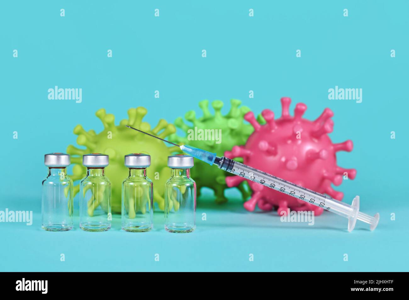 4 flacons de vaccins avec seringues et modèles de virus corona en arrière-plan Banque D'Images