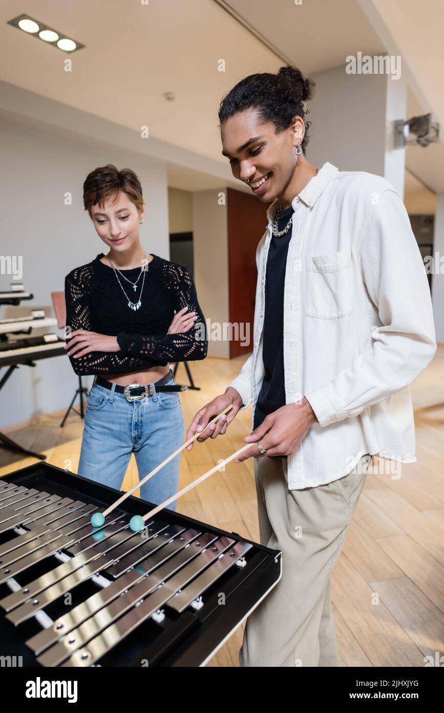 Vendeur américain africain positif jouant xylophone près de la femme dans le magasin de musique Banque D'Images