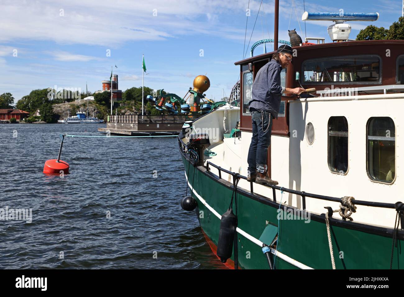 La vie quotidienne à Stockholm, en Suède, le dimanche. Un homme travaille avec son bateau à Djurgården. Banque D'Images