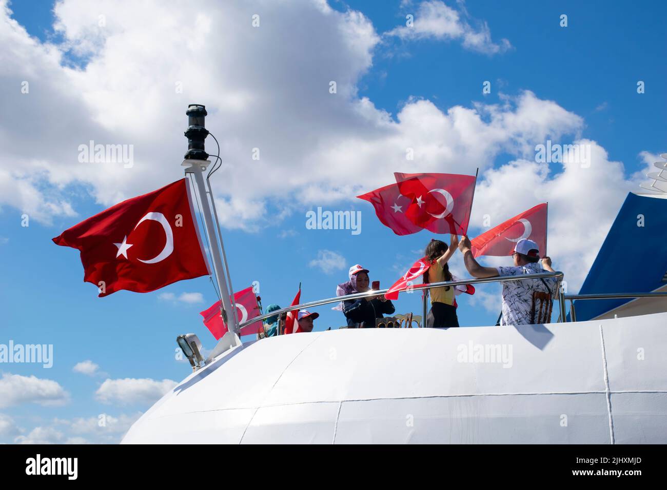 Turquie - juillet 2022 : une petite fille agitant le drapeau turc sur un navire. Jeune photographe féminine prenant la photo d'une petite fille qui agite le drapeau turc à bord. Banque D'Images