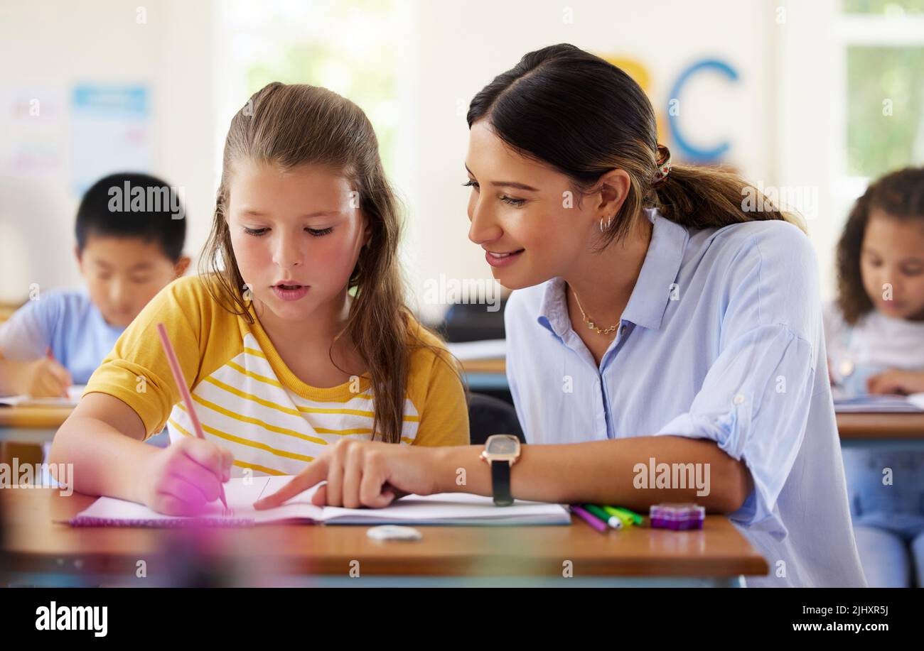 Heureux d'être en classe. Une enseignante aidant un apprenant préscolaire dans sa classe. Banque D'Images