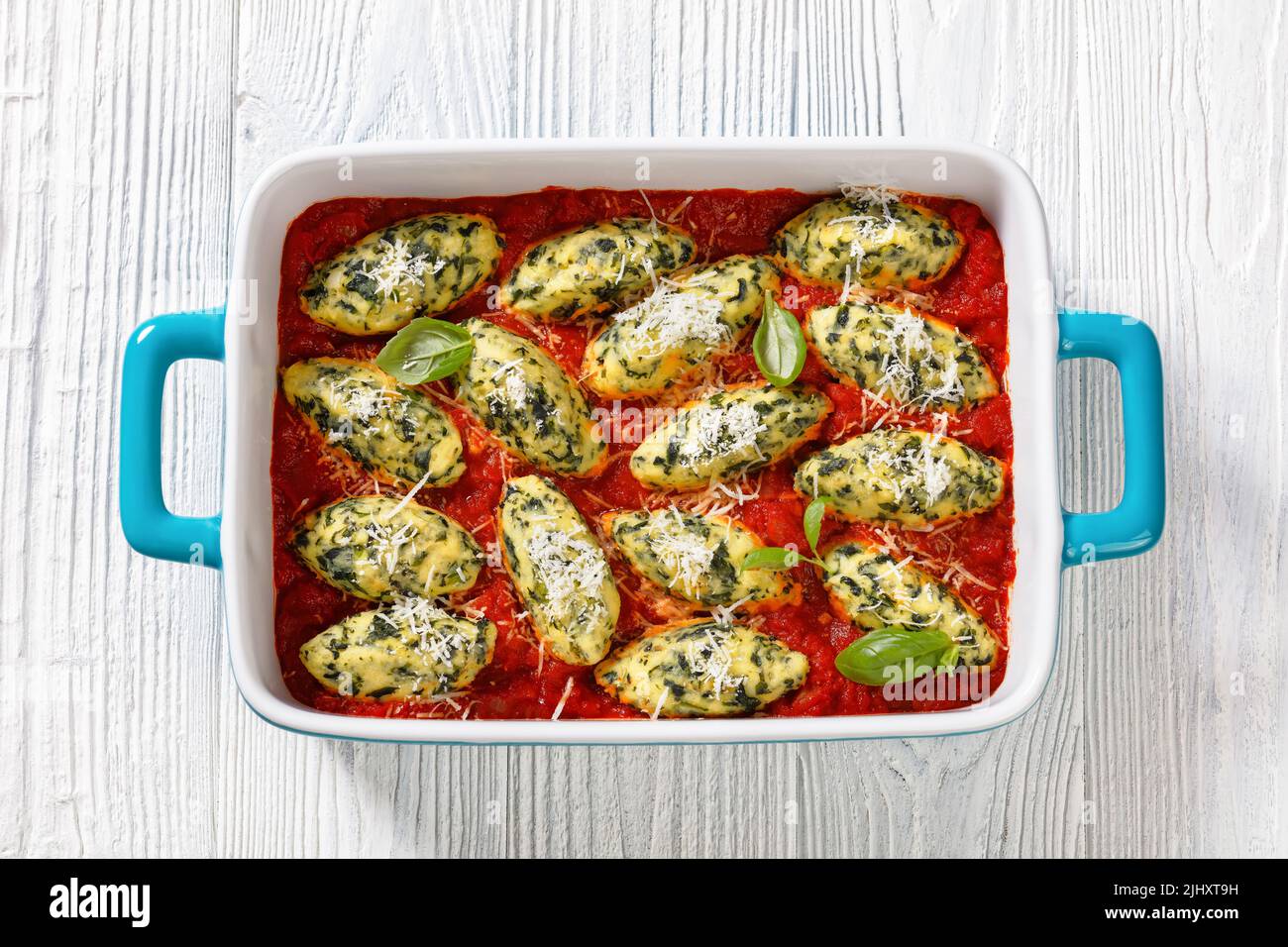 Boulettes de ricotta aux épinards italiens sauce tomate aux herbes et parmesan râpé dans un plat de cuisson en céramique sur table blanche, plat, cl Banque D'Images