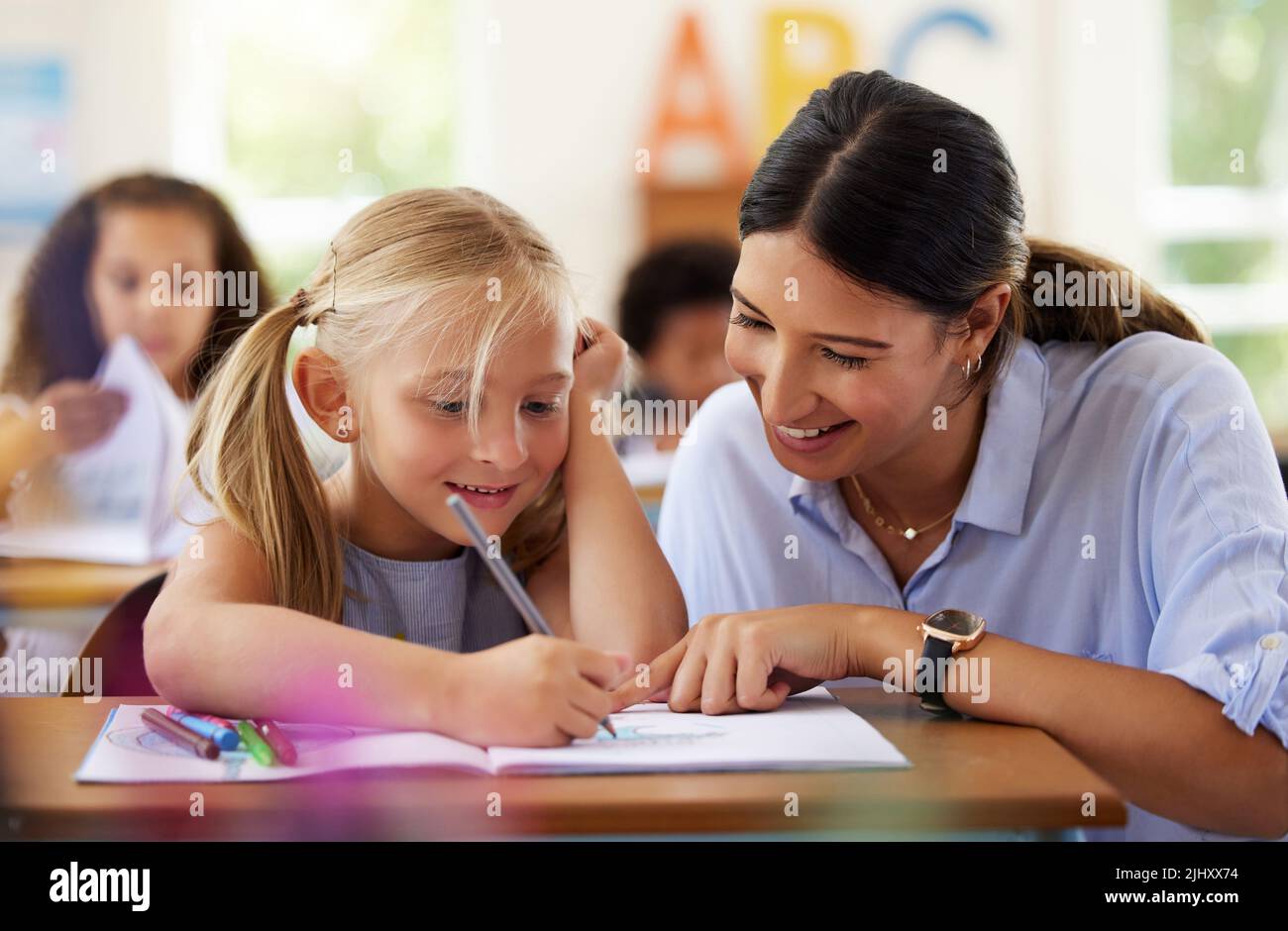 L'importance de l'éducation commence jeune. Une enseignante aide à un apprenant préscolaire dans sa classe. Banque D'Images